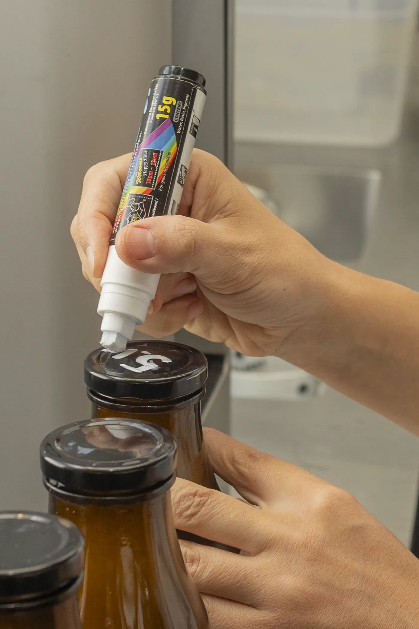 Glasflasche mit frischem Haferdrink wird von Hand beschriftet