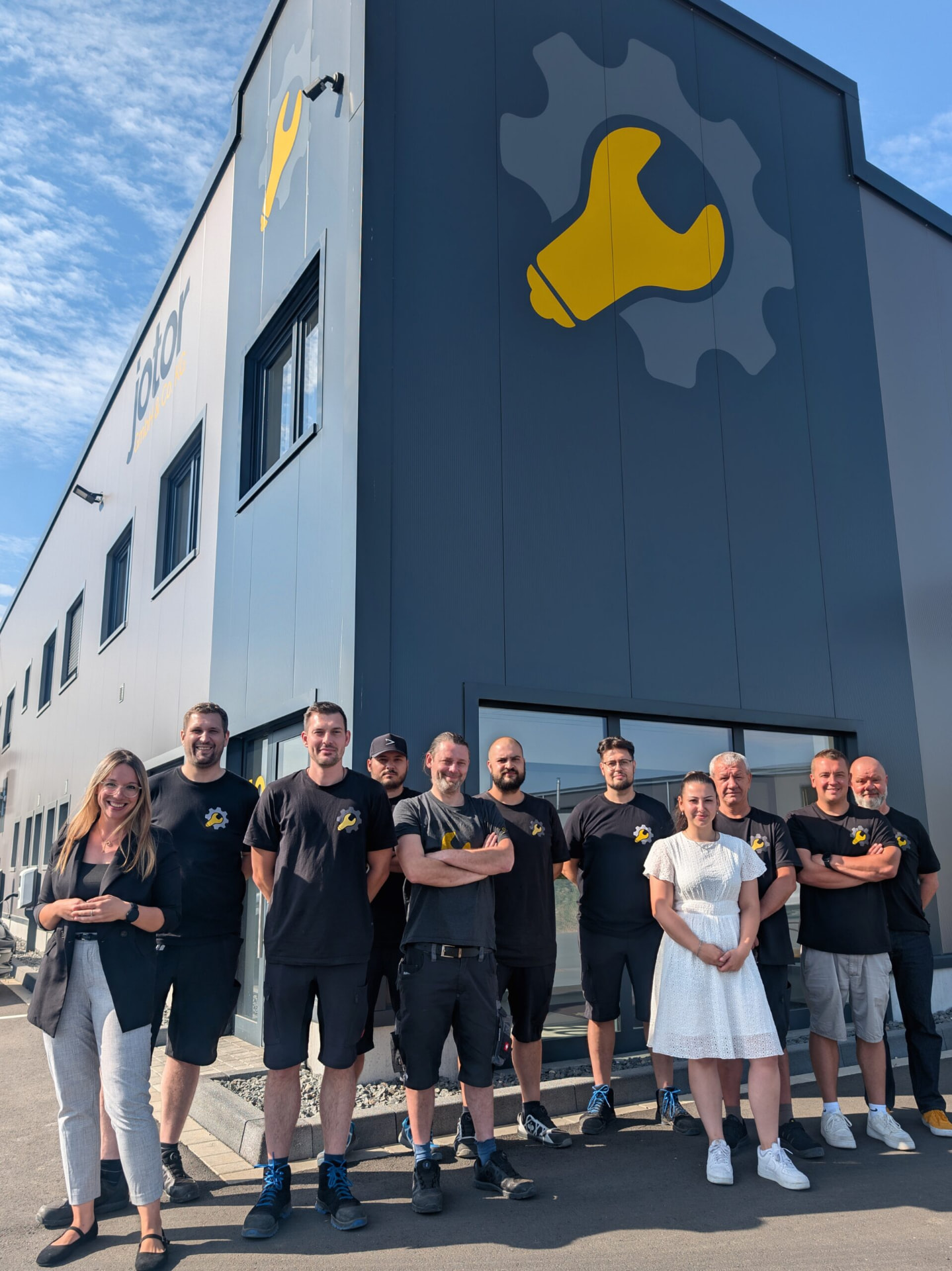 Elf Personen des Jotor-Teams stehen vor dem Firmenhaus in Rheinbach; an der Fassade sind das Jotor-Logo mit Zahnrad und Schraubenschlüssel sowie der Schriftzug jotor zu sehen