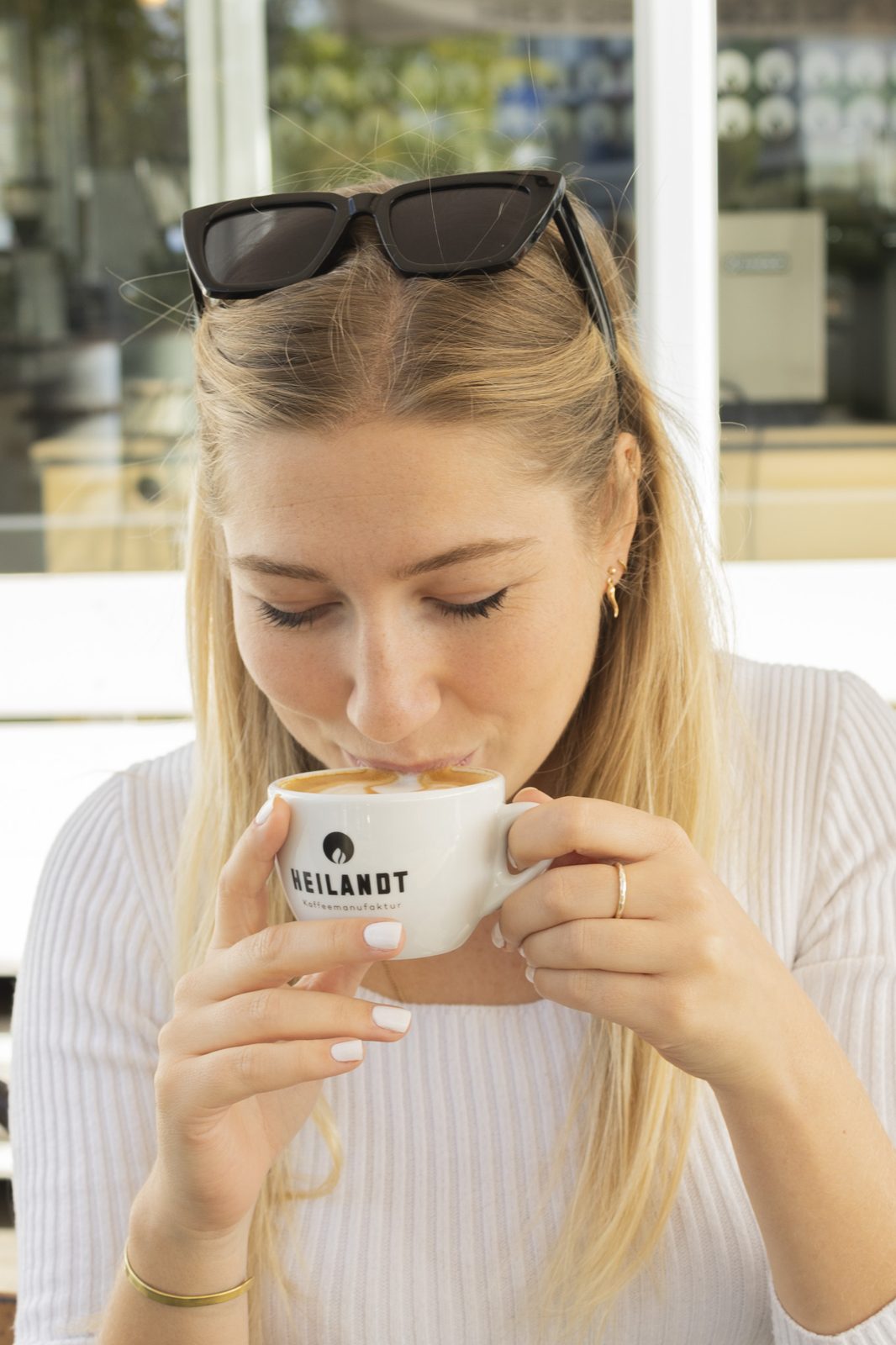 Frau trinkt mit geschlossenen Augen aus einer Kaffeetasse