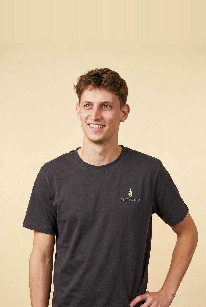 Porträt von Maximilian Weigt im dunklen T-Shirt mit The-Oater-Print vor cremefarbenem Hintergrund