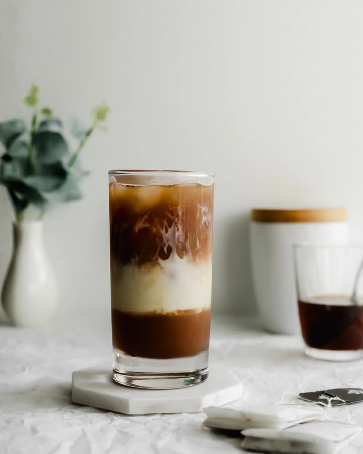 Dirty Earl Latte im hohen Glas mit Eiswürfeln, Haferdrink und Espresso in Schichten